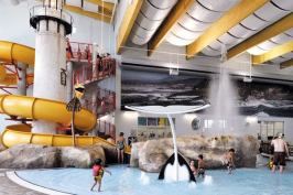 The Oregon-themed aquatics complex is a focal point for the facility. Play features for all ages include a water slide that wraps around a scaled-down replica of the Yaquina Head lighthouse, north of Newport, Ore. The slide plunge pool is surrounded by rock theming and includes a blowhole modeled after a natural feature at Depoe Bay. The blowhole is activated as bathers plunge into the splash zone at the bottom of the slide. Other amenities are floor geysers, interactive spray features, a vortex, and a lazy river that winds through a forest of artificial coniferous trees and doubles as a resistance channel for exercise, therapy and rehabilitation.
