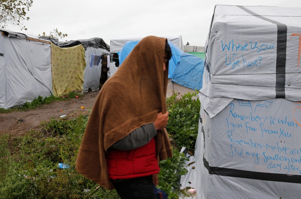A migrant walks past tents and shelters in the makeshift camp called the "New Jungle" as unseasonably cool temperatures arrive in Calais, northern France, October 21, 2015. The number of migrants camped on France's north coast near Calais has doubled to around 6,000 in recent weeks, boosted by an influx across Europe's borders. Migrants and refugees are camped in Calais, fleeing war and poverty in the Middle East, Africa and Asia and now living in the jungle. Most of them are hoping to make the crossing to England.   REUTERS/Pascal Rossignol - RTS5GCR