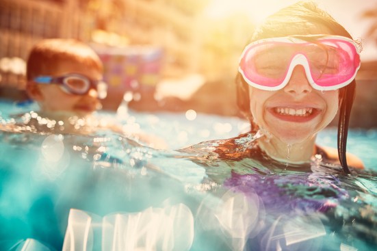 Kids swimming, laughing and having fun in hotel resort pool.