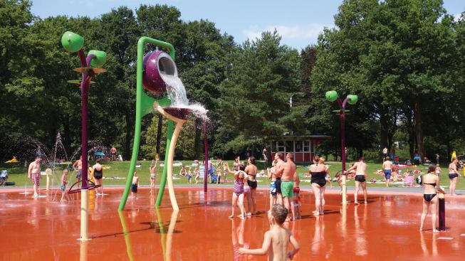 The spraypads are connected by a path and common materials, lines and colors. Light and dark greens project the look of grasses in various stages of growth, while blues, yellows, reds and plums draw attention.