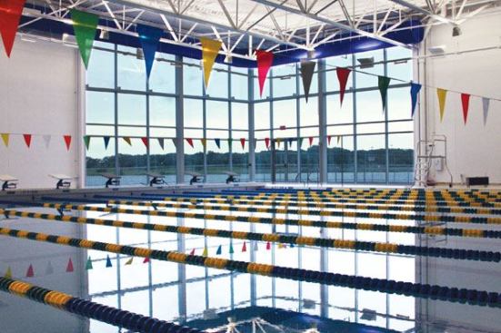 Abundant natural light and views provide a welcome alternative to the dark, windowless spaces of many comparable facilities. Translucent wall panels along the mezzanine’s south wall are protected from glare by a large overhang, which diminishes solar heat gain in summer and provides a

soft filtered light to its interior spaces. With spectator views directed northward, architects were able to locate floor to roof glazing at the pool’s northeast and northwest corners,allowing indirect northern light and providing views to adjacent lake and park areas.