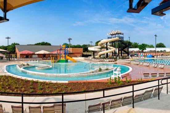 In planning for aquatic amenities, designers had to balance site challenges with the needs of the community. The goal was not to create a space that appears too forced or engineered. Aquatic, architectural and landscape design are seamlessly integrated into a cohesive whole. Aquatic

amenities include a 4-lane lap pool cascading across a wet deck into a leisure pool with zero-beach entry, and current channel. A climbing wall, a water slide tower, interactive play features and a separate tot pool round out the mix.